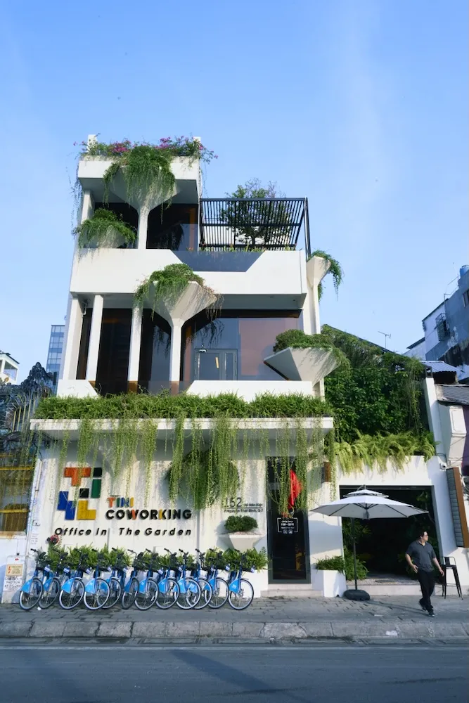 Our office building, a white house covered with green plants, with a TINI Coworking sign